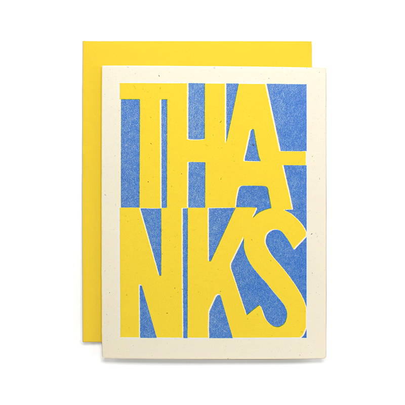 A square greeting card with a yellow envelope behind it, featuring the word 'THANKS' in large yellow letters over a blue textured background on an off-white cardstock.