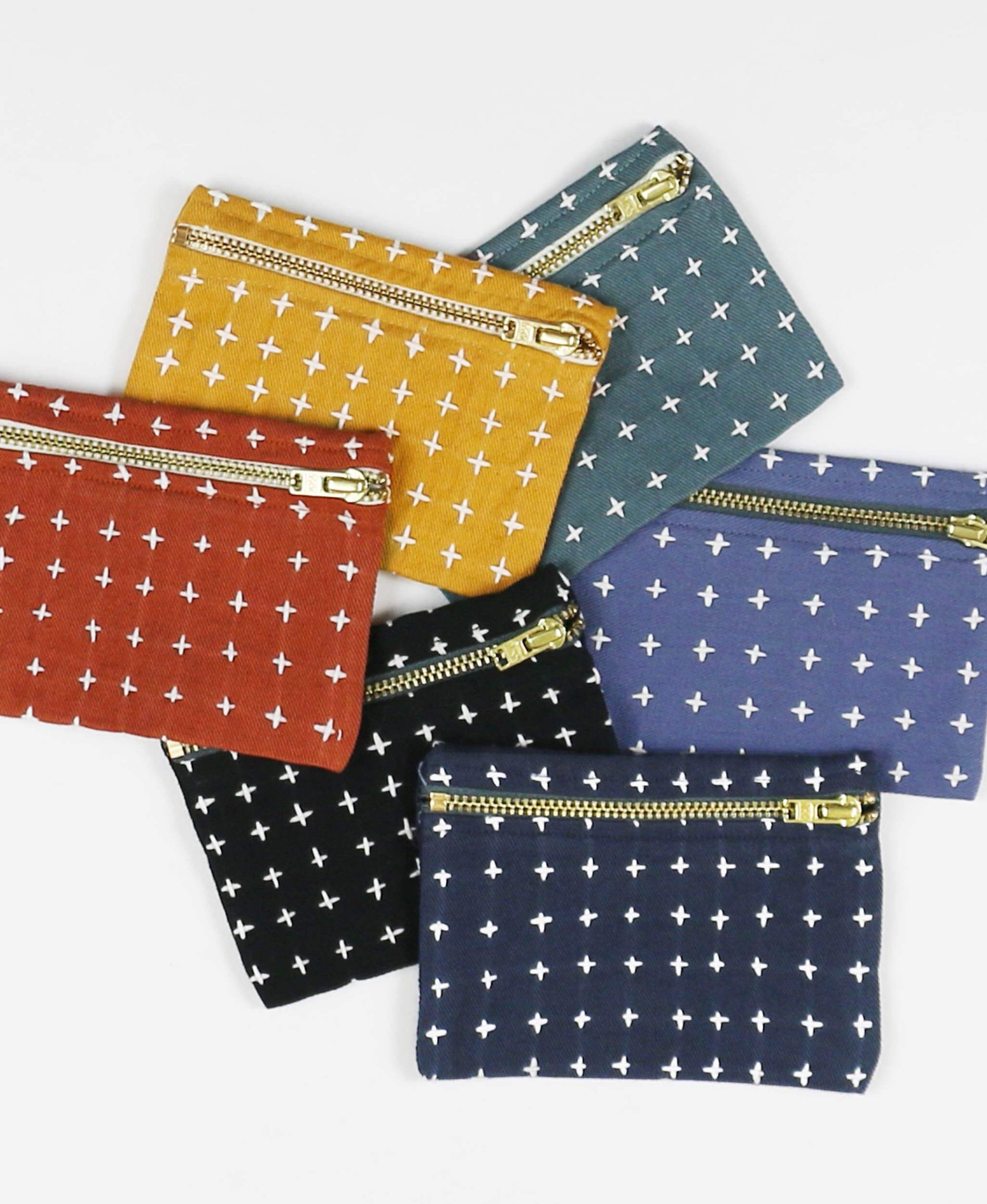 Set of colorful pouches with star patterns and gold zippers on a white background