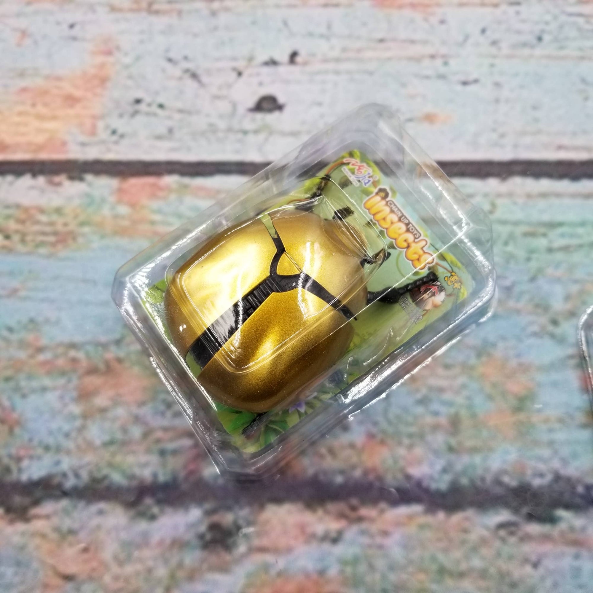 Gold-colored product in clear packaging on a textured surface