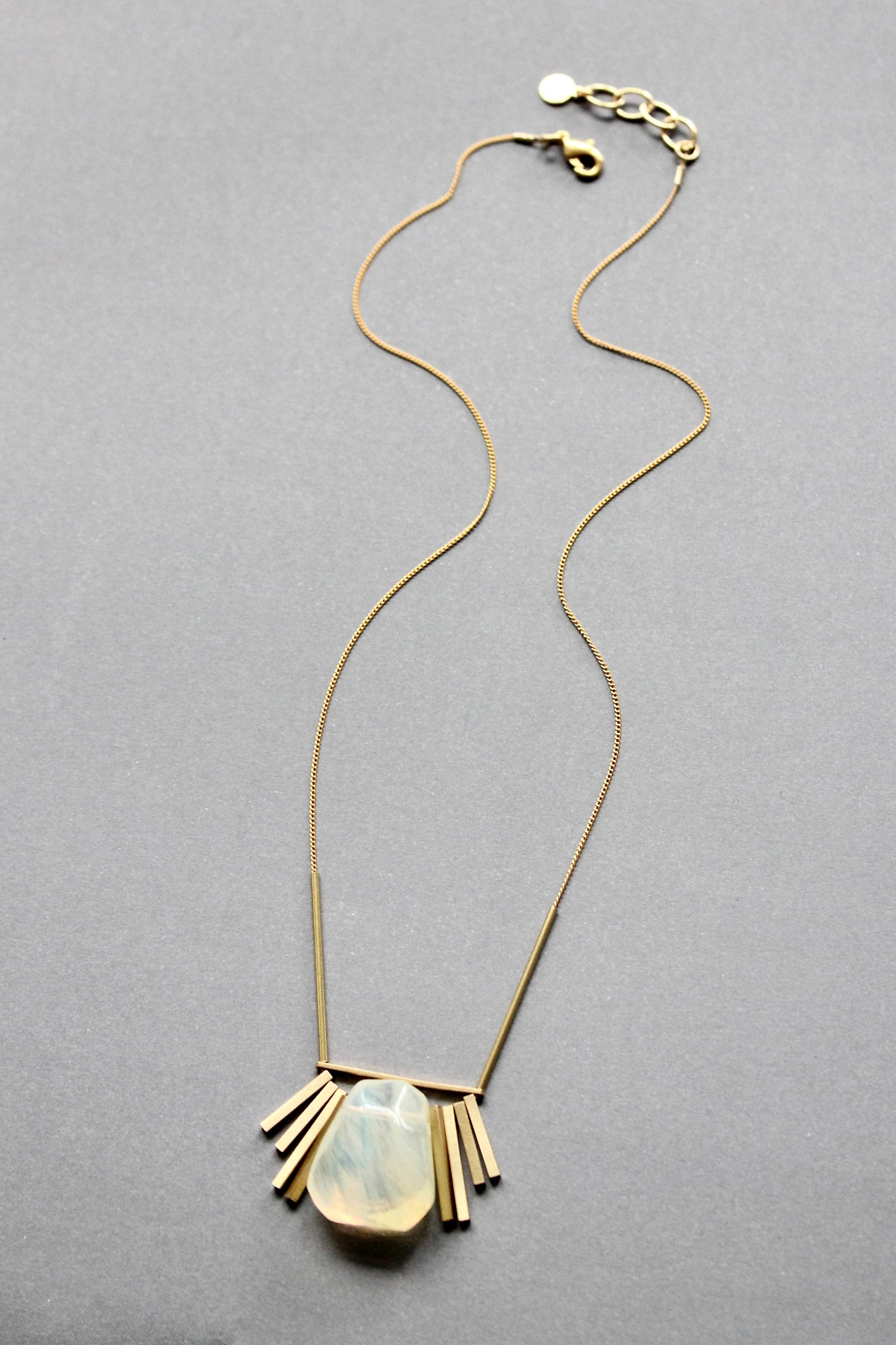 Gold necklace with a pendant on a gray background