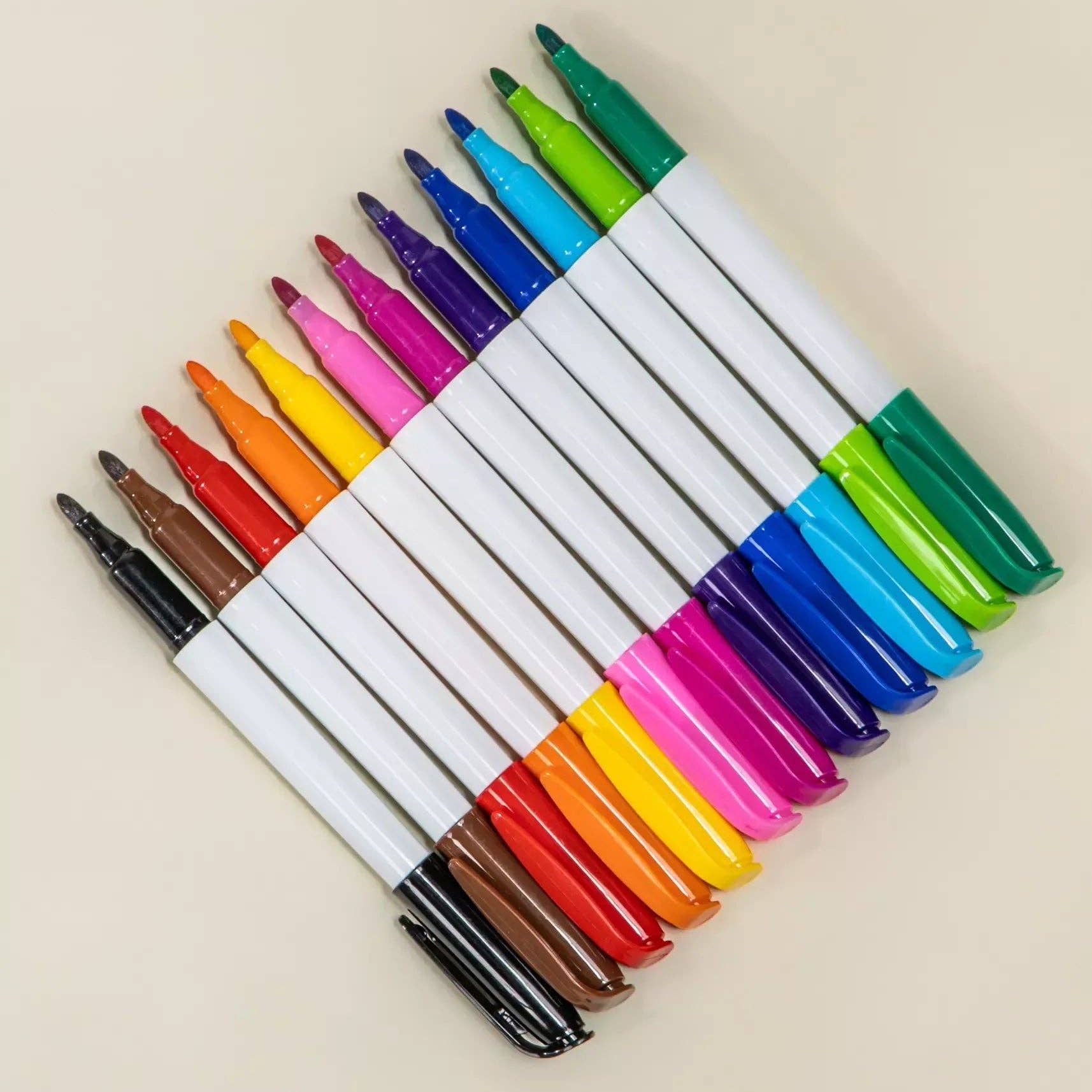 Set of colorful markers arranged in a fan-like pattern on a beige background