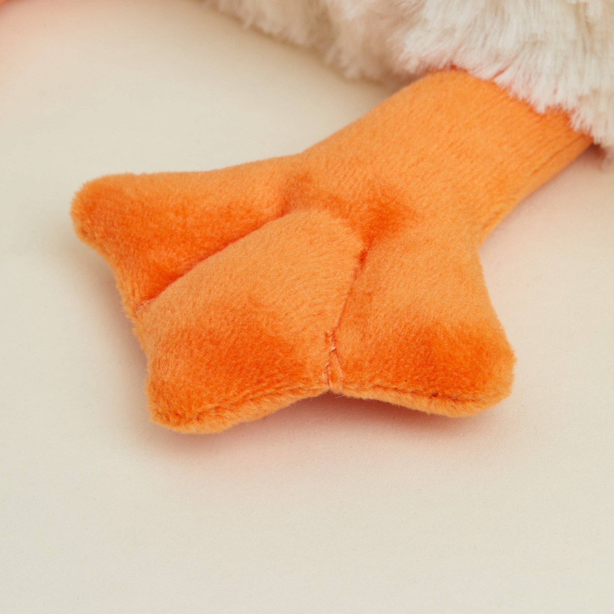 Close-up of an orange plush toy on a beige background