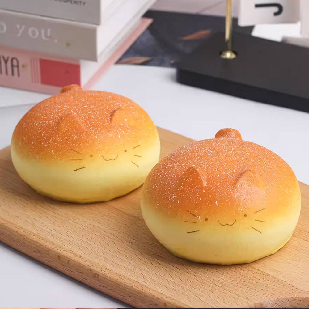 Two cat-shaped bread buns on a wooden board with a blurred background