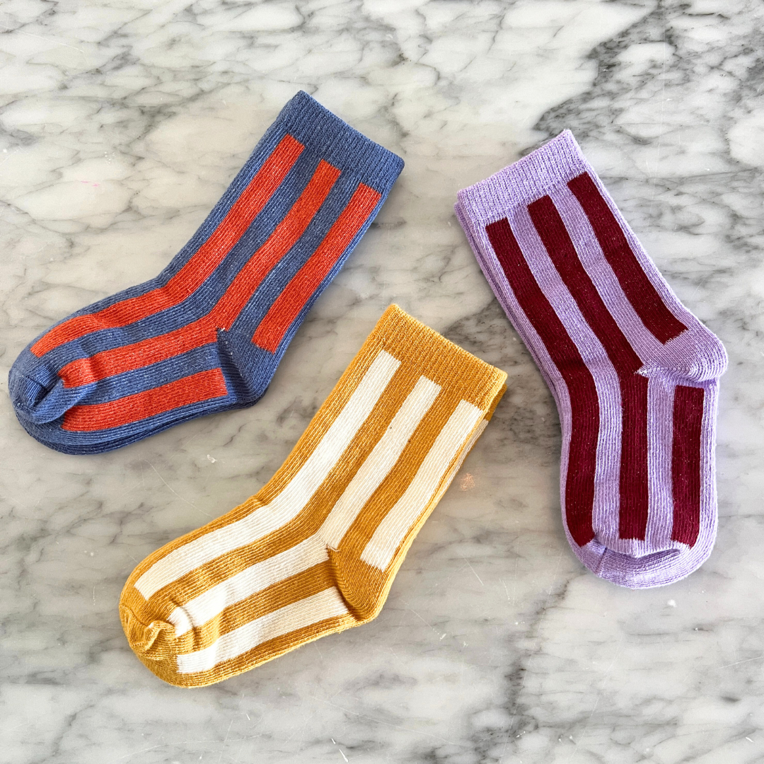 Three pairs of striped socks on a marble surface