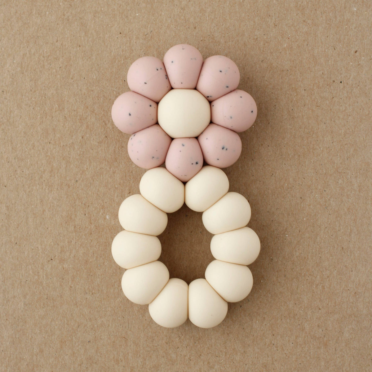 Decorative letter 'A' made of pink and white beads on a brown background