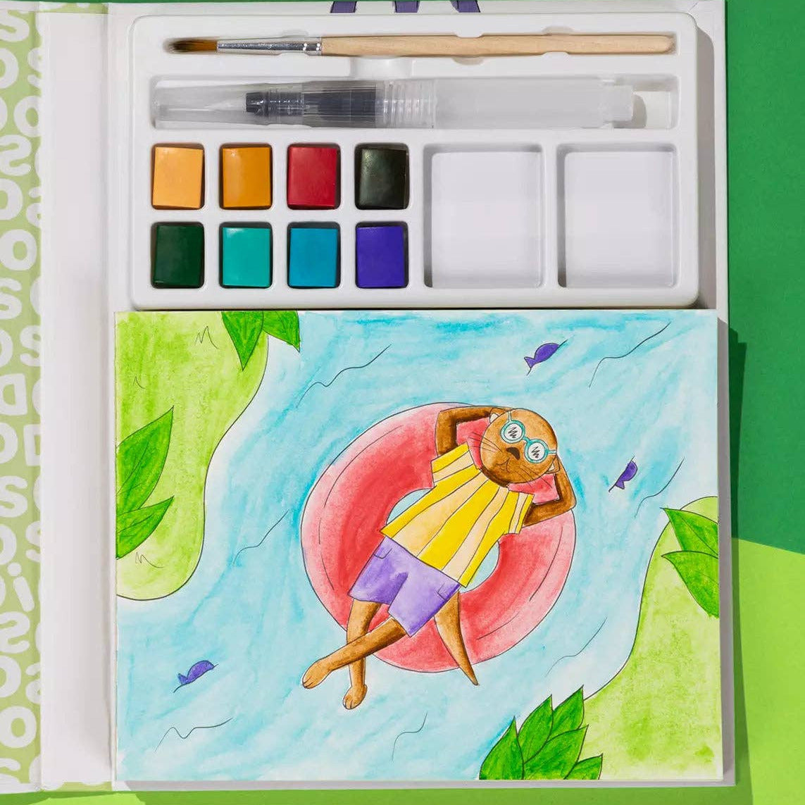 Watercolor set with a painting of an otter on an inflatable ring on a green background