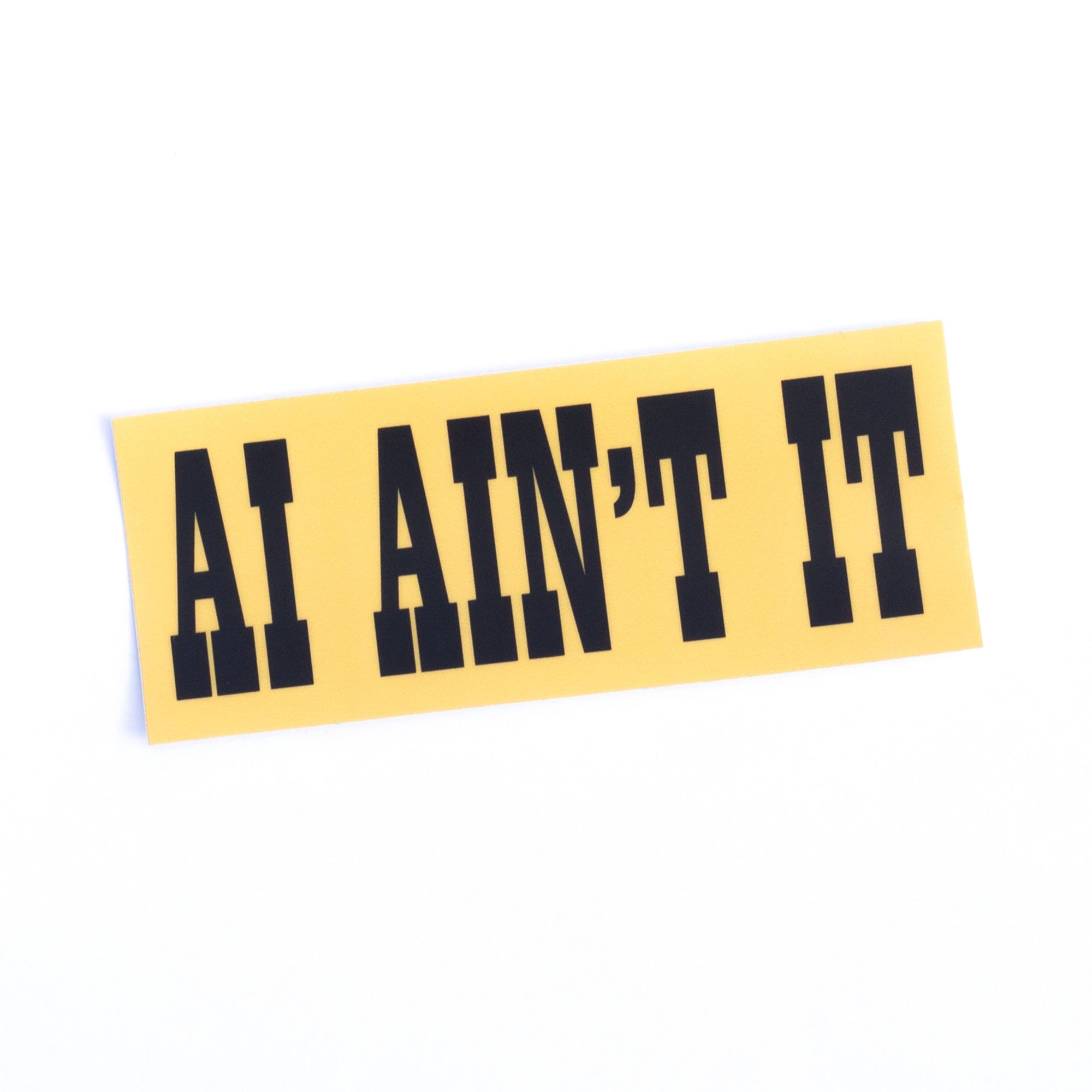 Yellow bumper sticker with black text 'AI AIN'T IT' on a white background