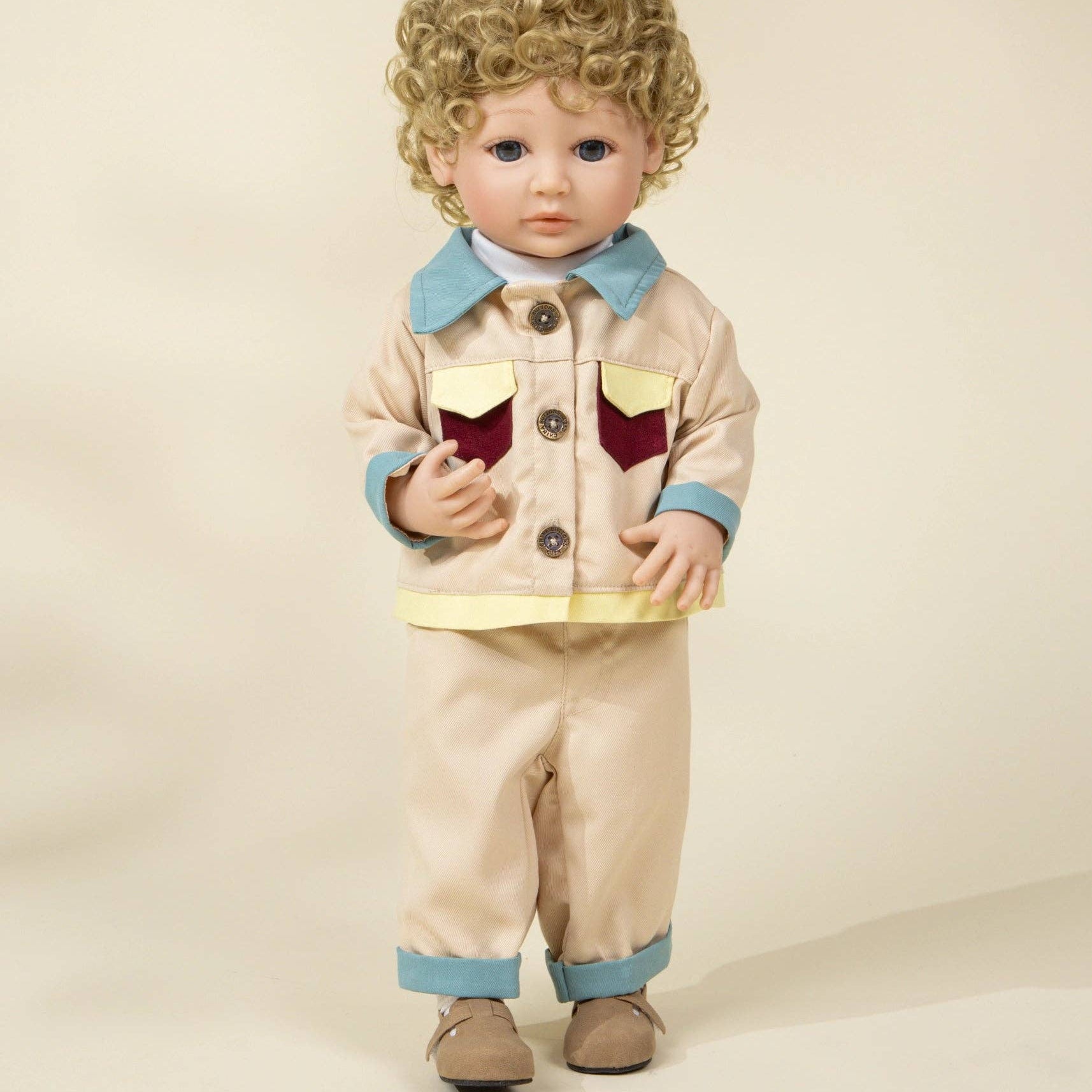 Doll wearing a beige outfit with a blue shirt and brown shoes on a beige background