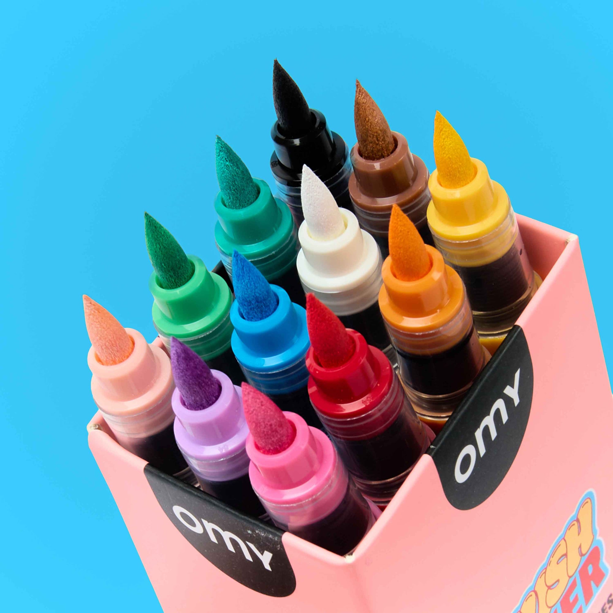 Set of colorful bottles with different colored caps in a pink holder on a blue background, featuring the brand 'omy'.