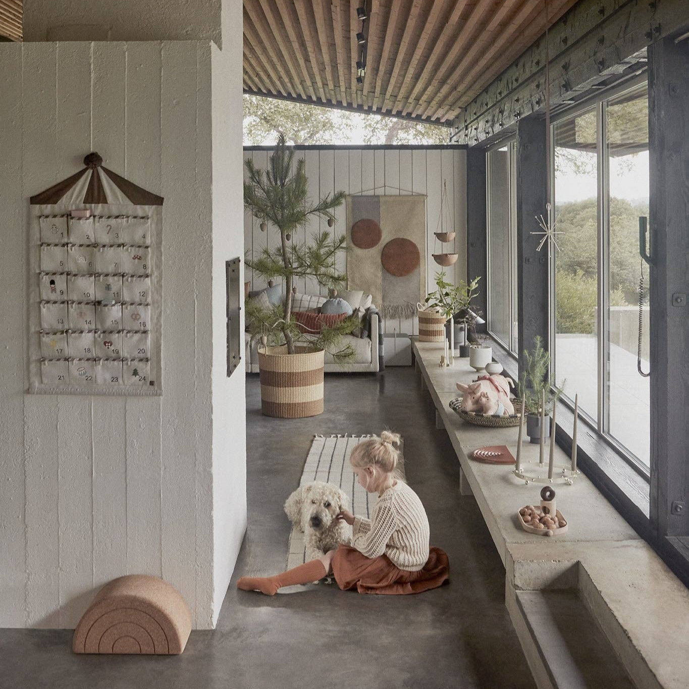Modern interior with wooden ceiling, large windows, and a child sitting on the floor with a dog.