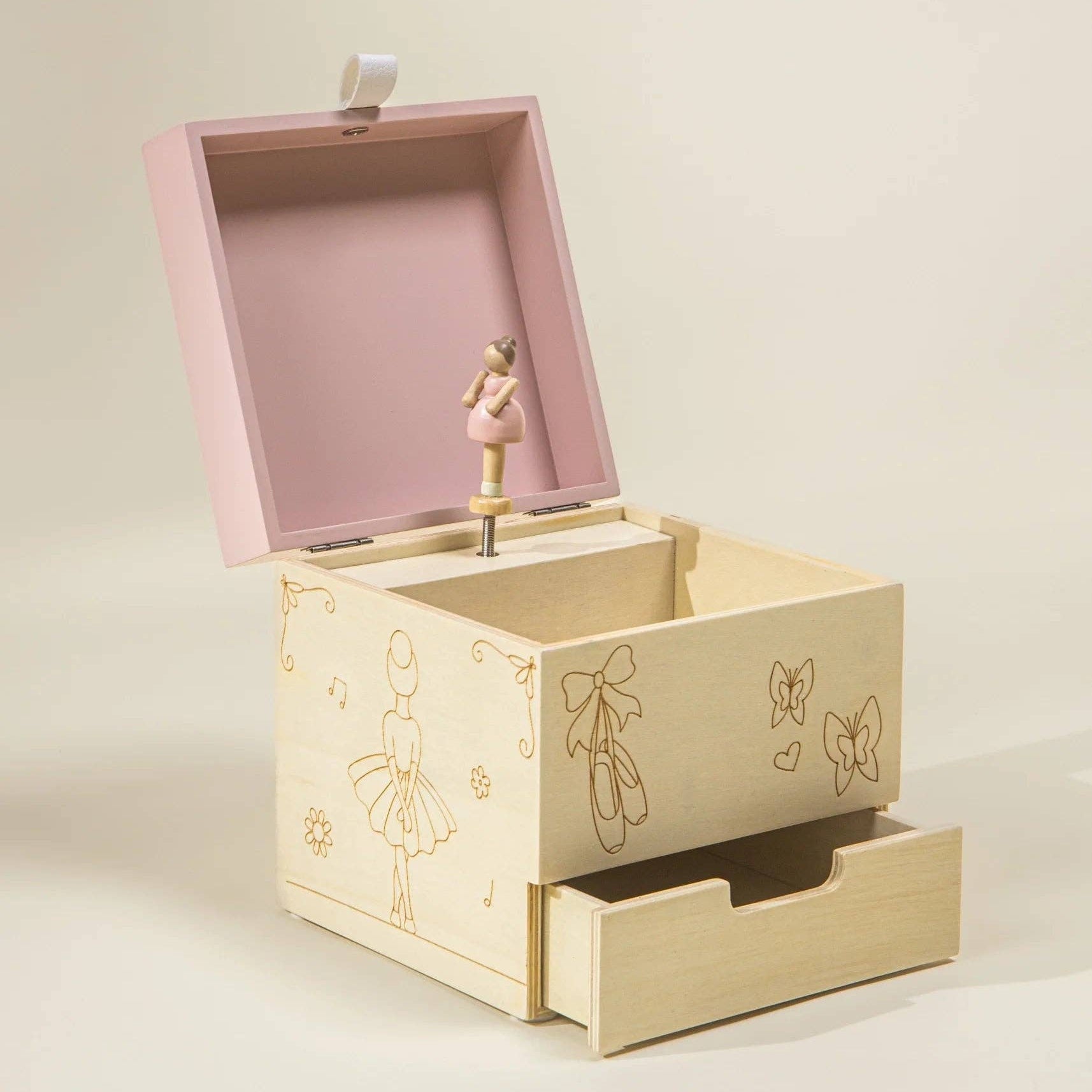 Wooden music box with pink top and ballerina design on a beige background