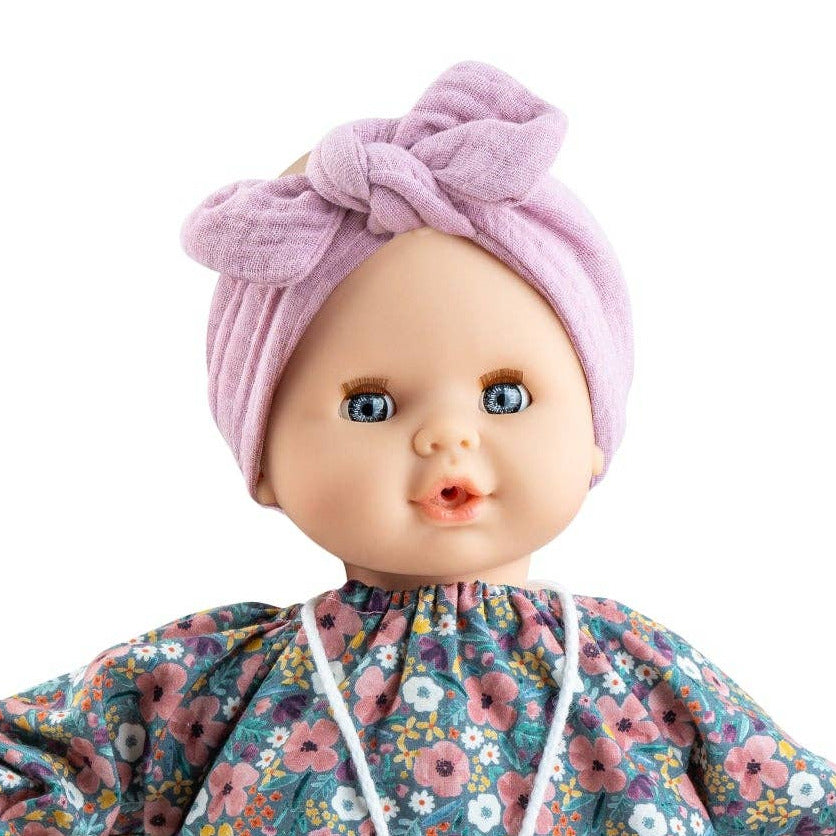 Baby doll wearing a floral dress and purple headband on a white background