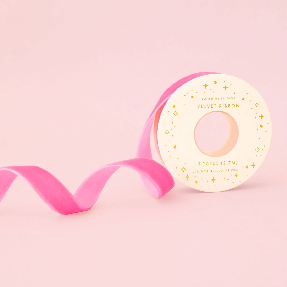 Pink velvet ribbon with a decorative label on a pink background