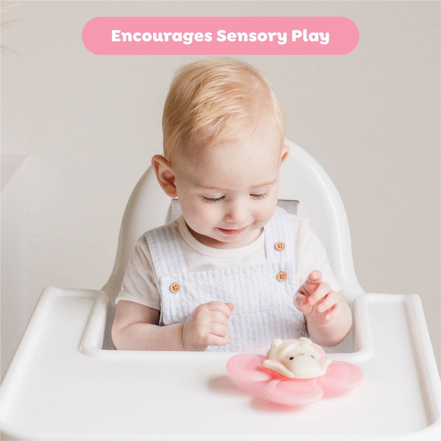 Child playing with a toy in a high chair, with text 'Encourages Sensory Play' above.