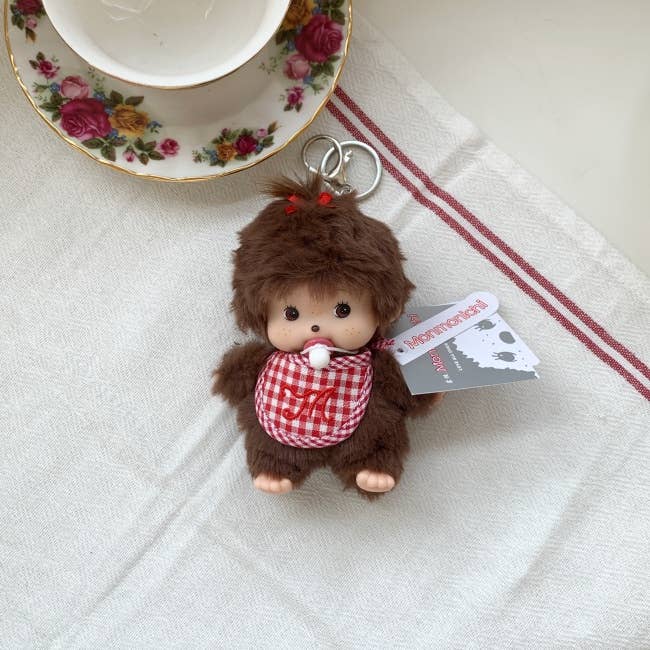 Small monkey plush toy with a checkered outfit on a white cloth background