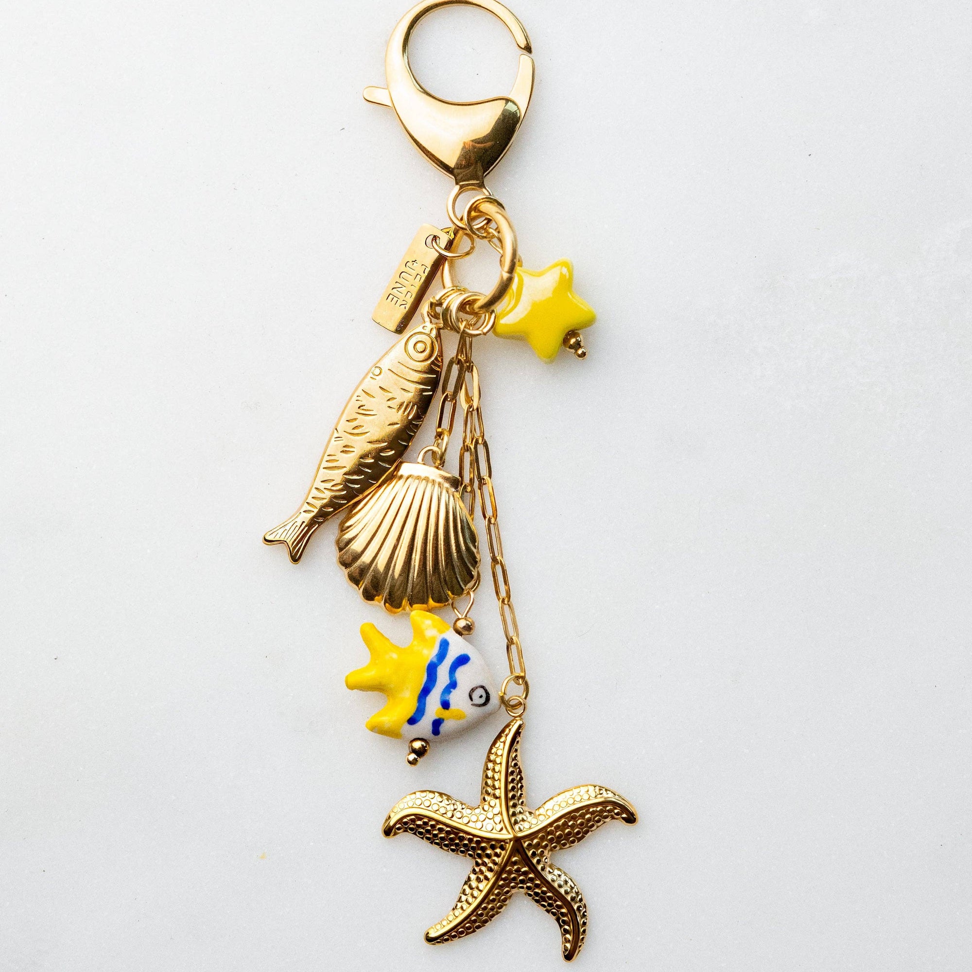 Gold keychain with sea-themed charms on a light gray background