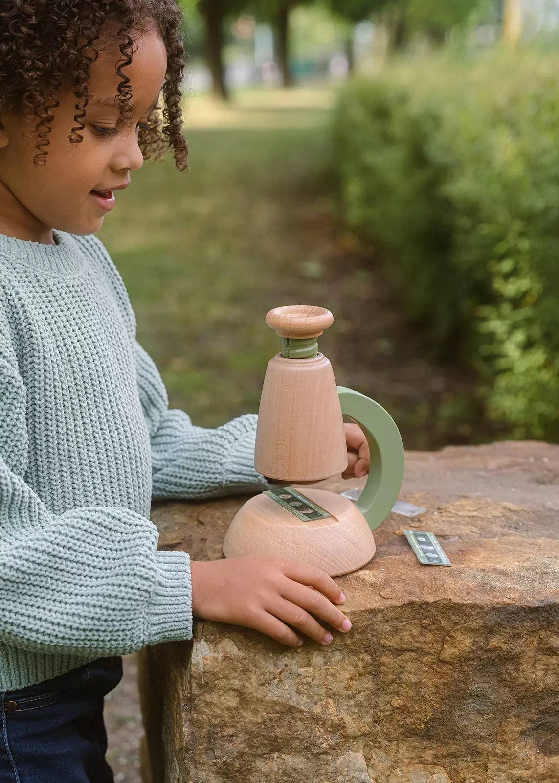 Child playing with wooden toys on a stone surface outdoors
