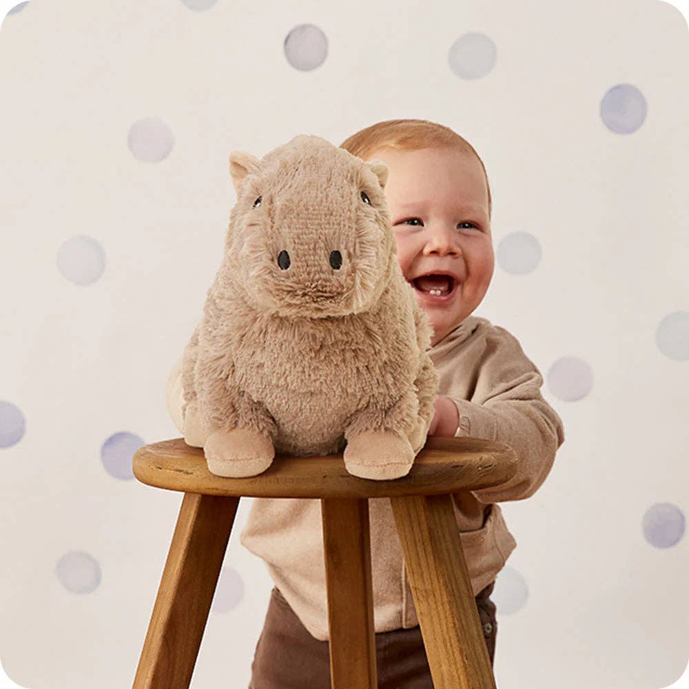 Child with a plush toy on a stool against a polka dot background