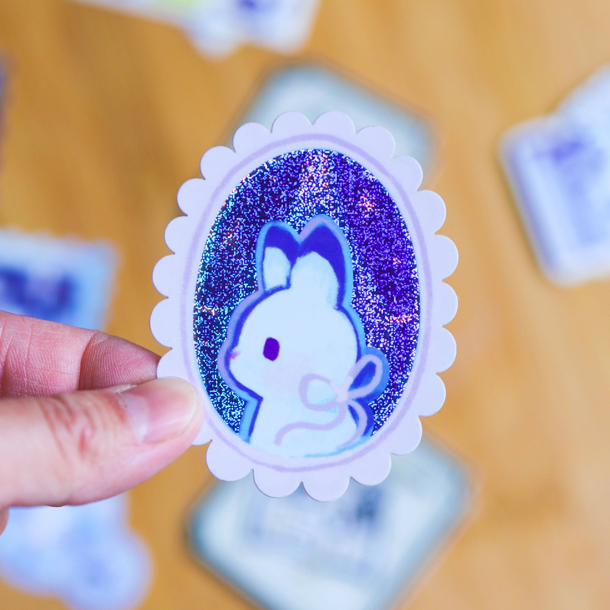Sticker with a rabbit design held by a hand on a blurred background