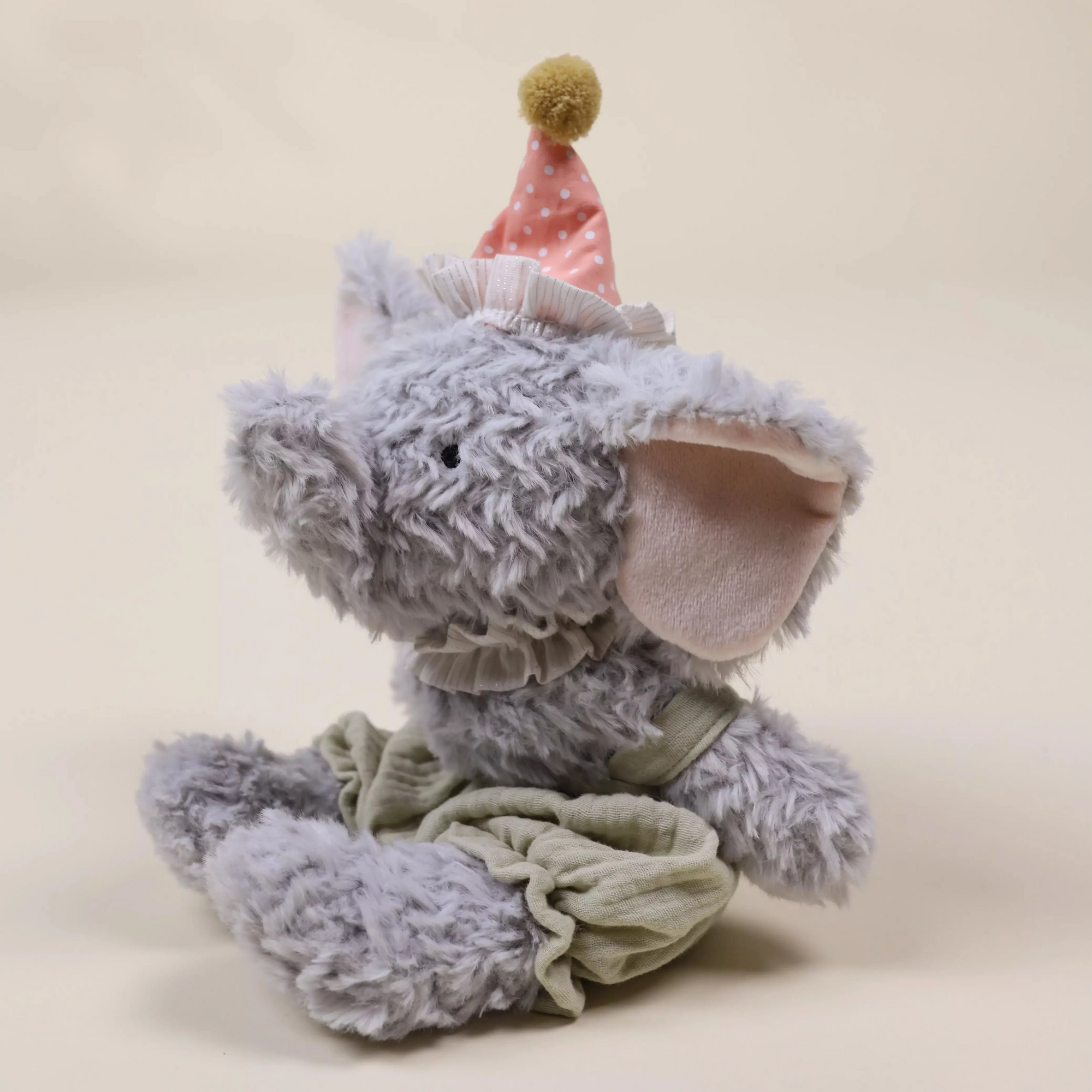 Plush elephant toy with a party hat on a beige background