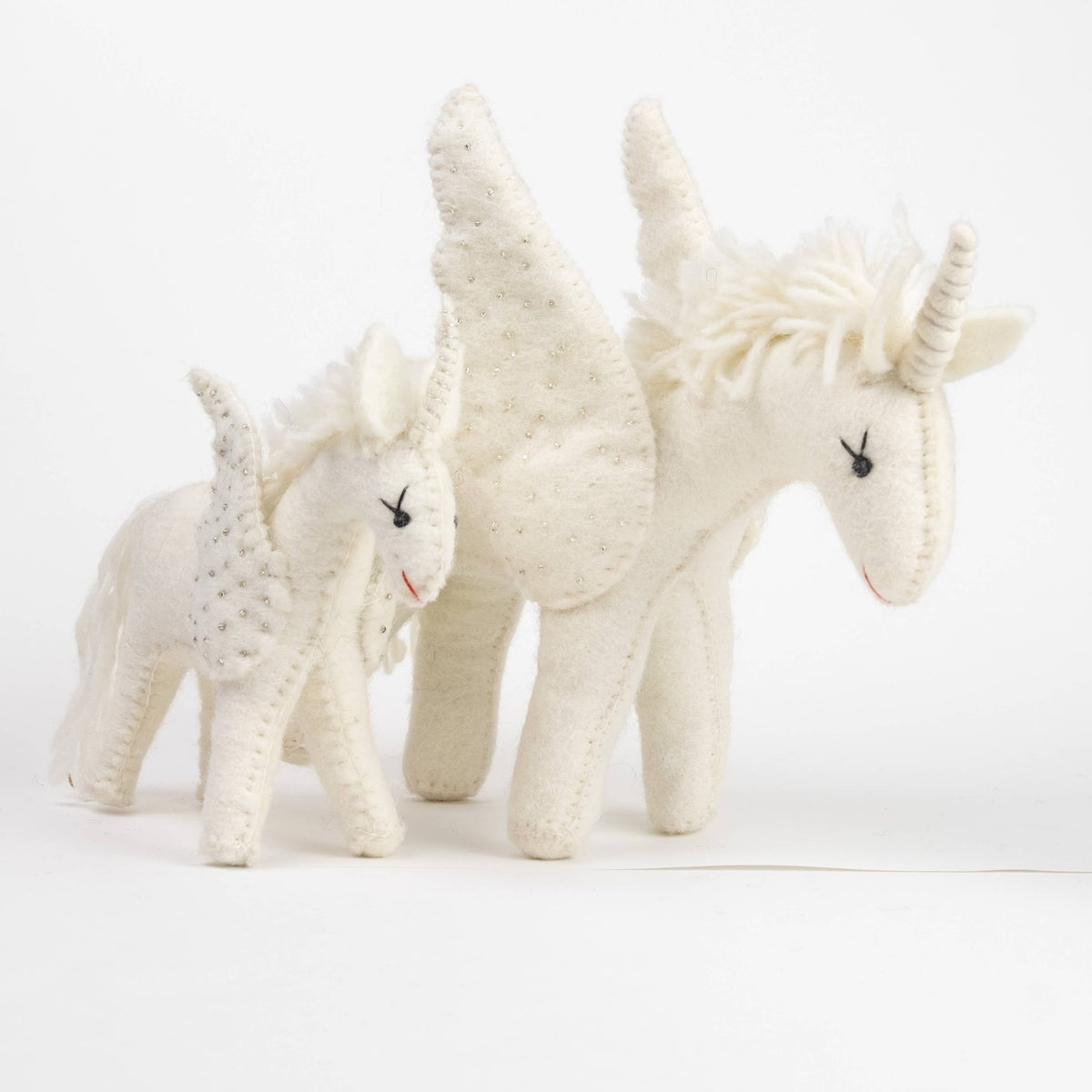 Three white unicorn toys on a white background