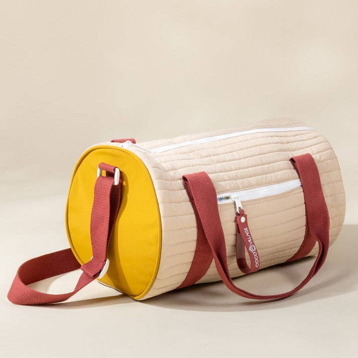 Round bag with yellow top half and beige bottom half on a beige background