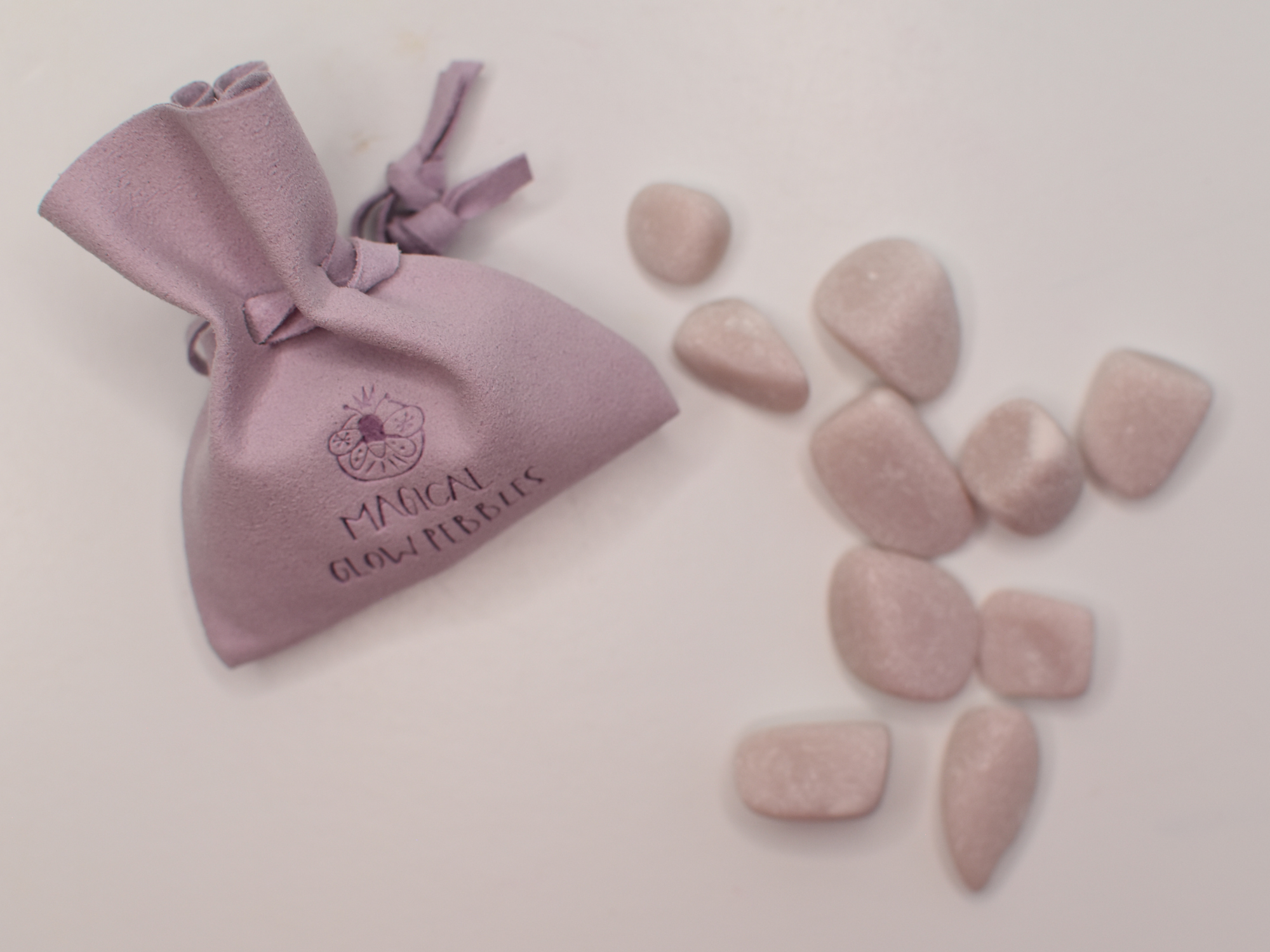 Pink stones and a matching drawstring bag on a light pink background