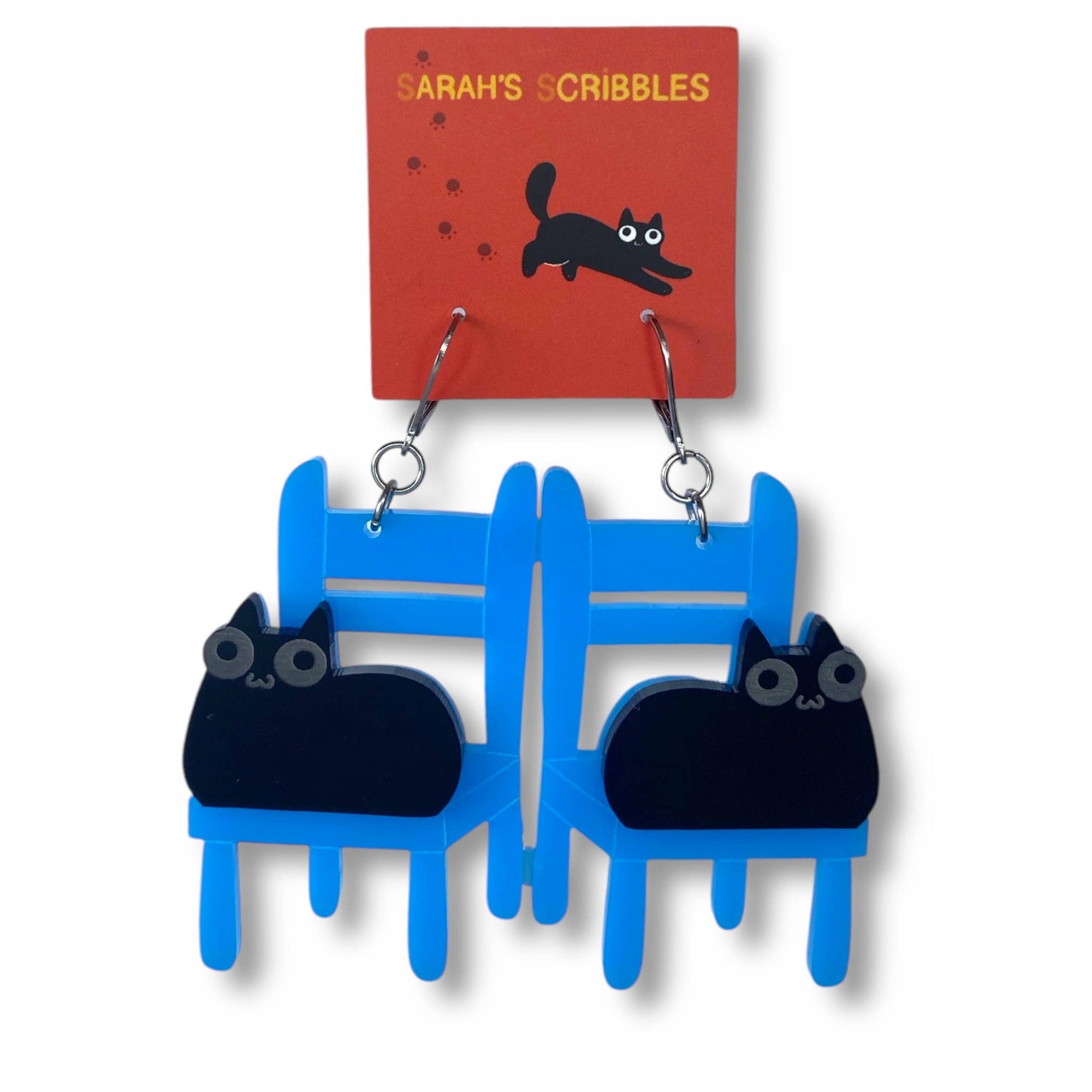 Blue and black cat-shaped earrings on a 'Sarah's Scribbles' branded card.