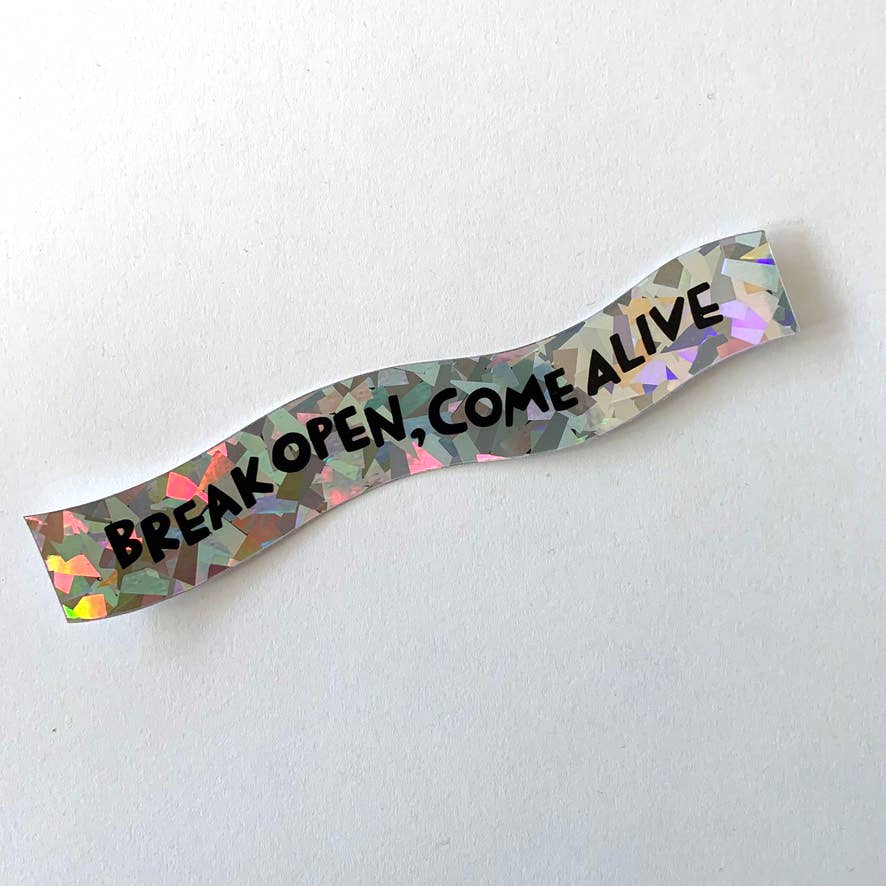 A wavy, holographic wristband sticker with the text 'BREAK OPEN, COME ALIVE' in black, displayed on a textured white background.