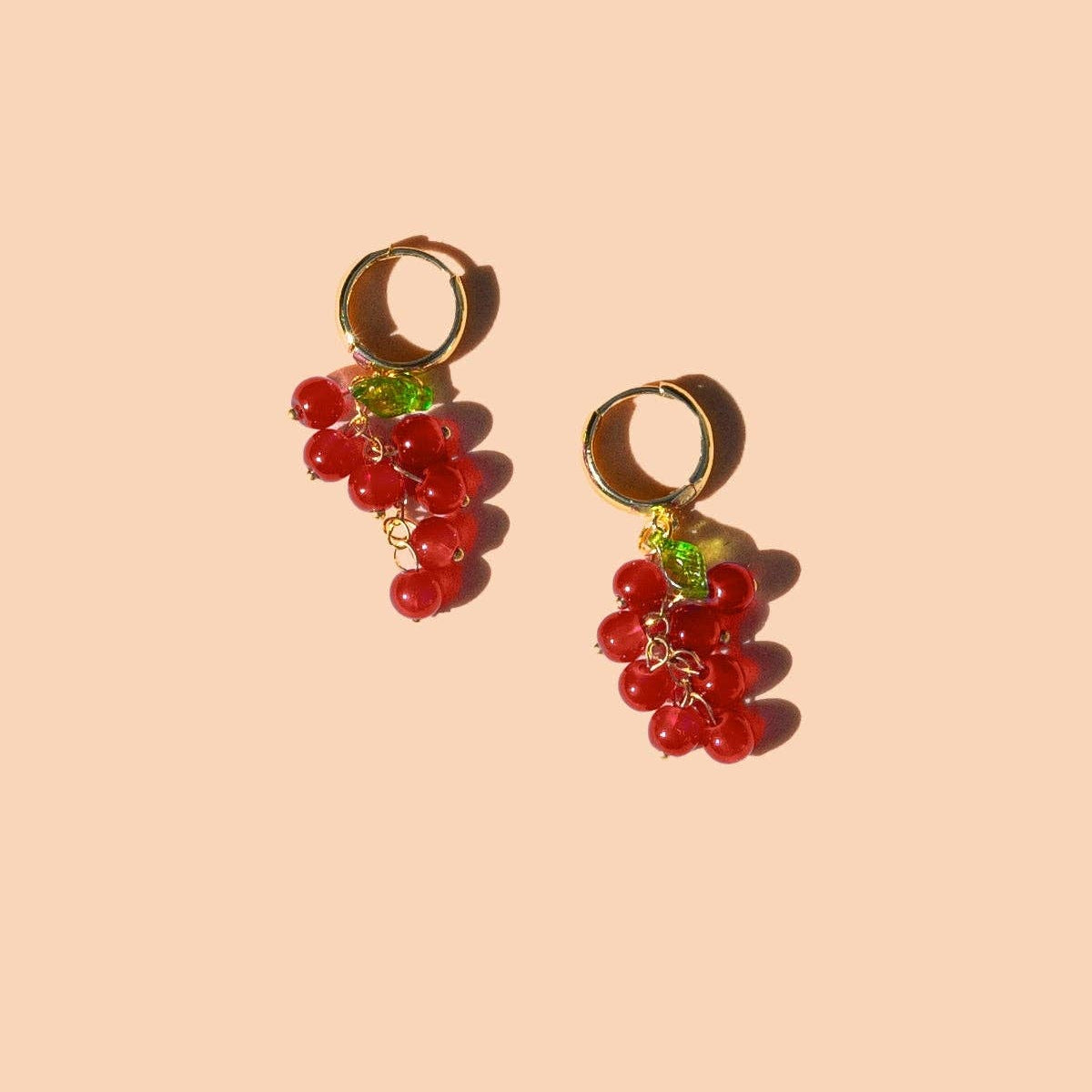 Grape-shaped earrings on a beige background