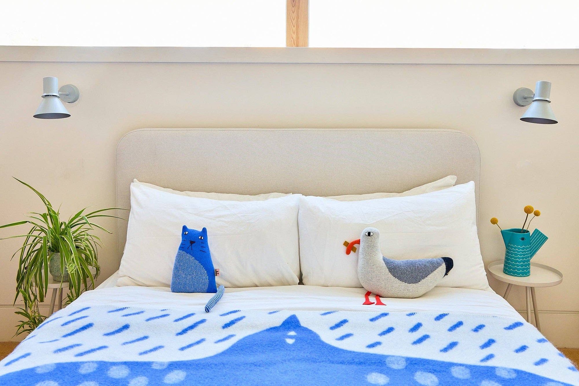 Bedroom with a bed featuring animal-shaped pillows and a blue and white patterned blanket.