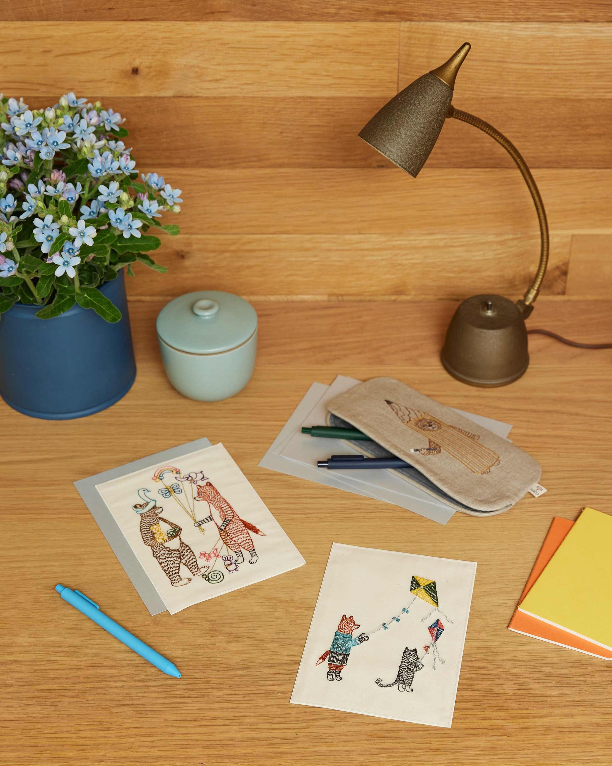 Desk with greeting cards, stationery items, and a lamp on a wooden surface