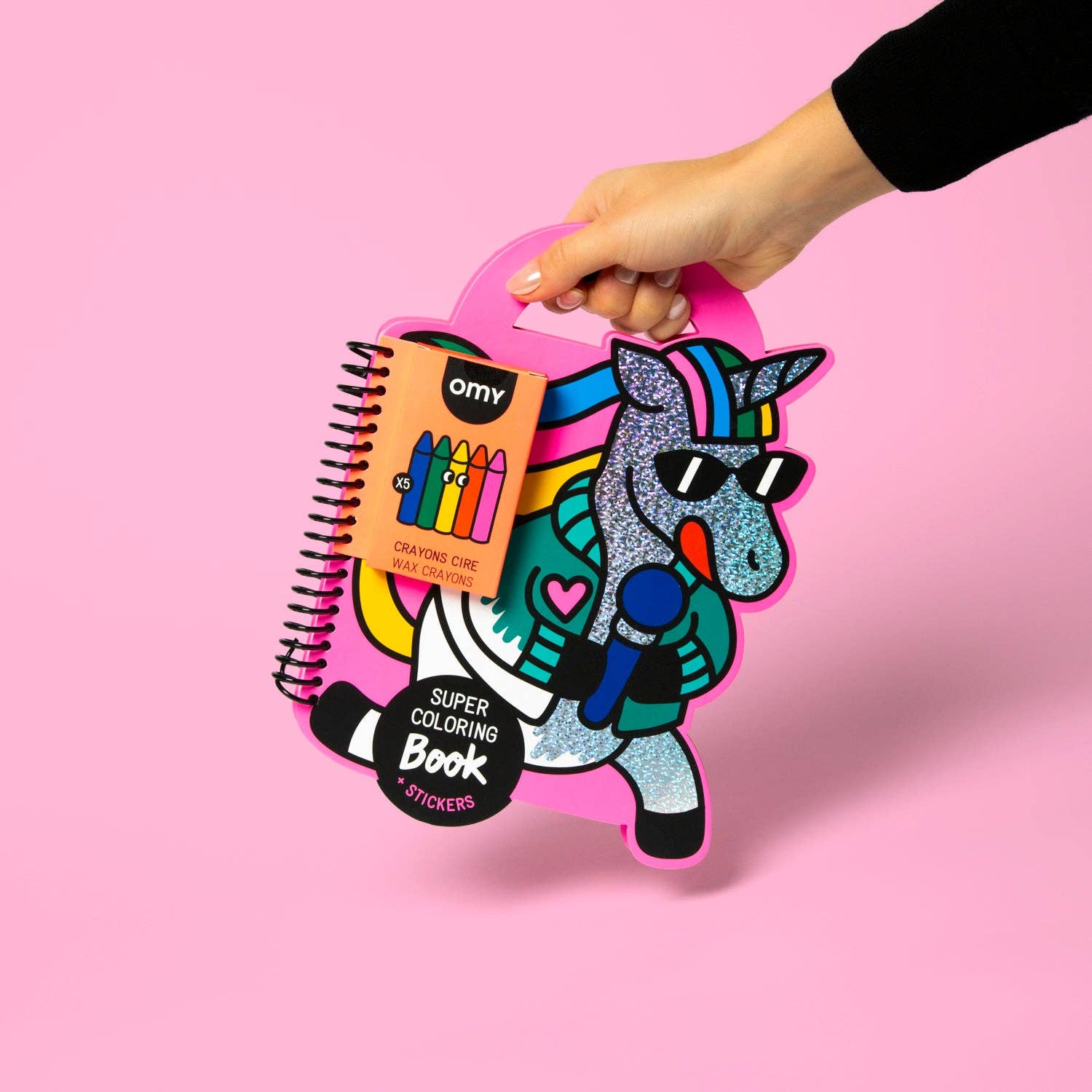 Colorful coloring book with a unicorn design held by a hand against a pink background