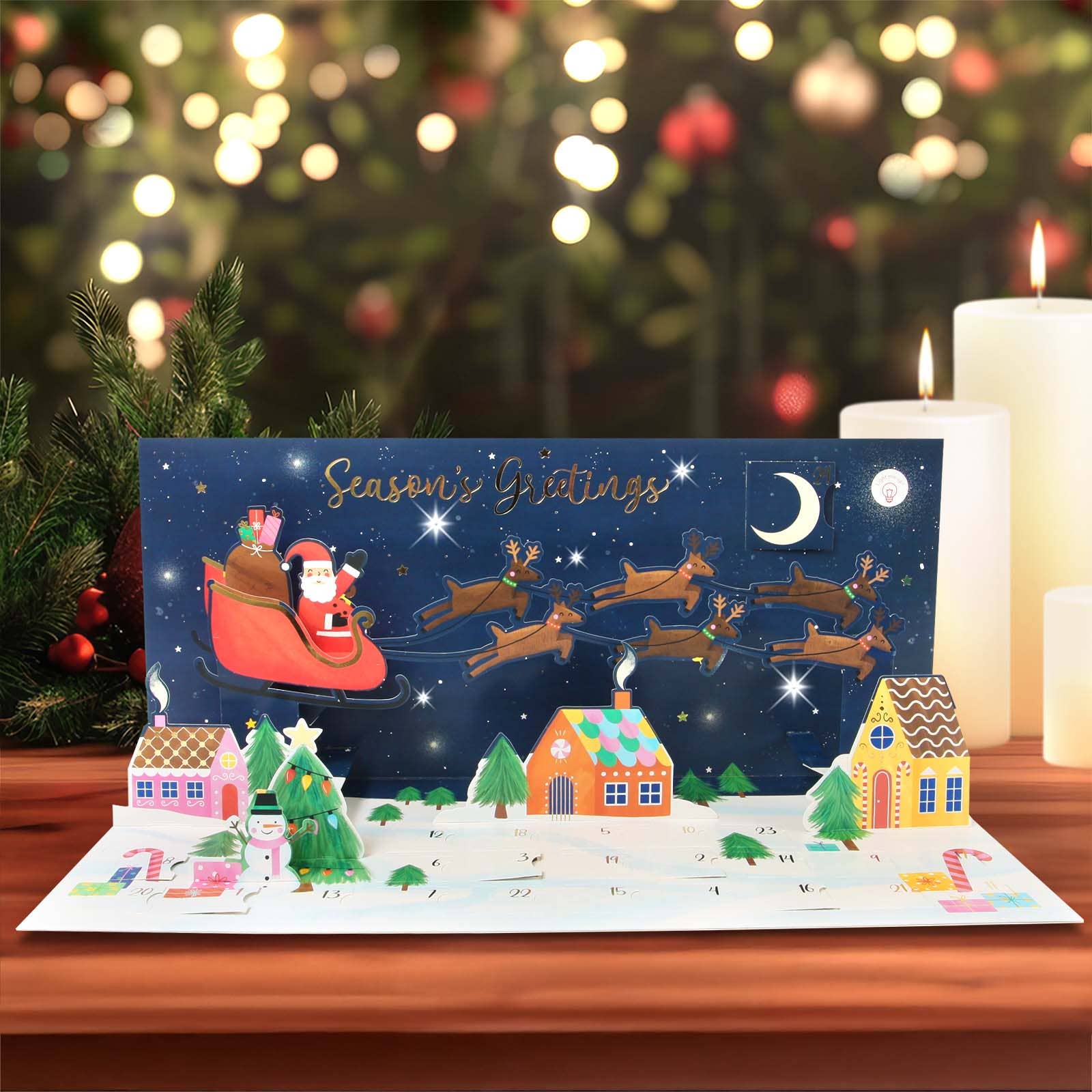 Christmas-themed pop-up card with Santa Claus and reindeer on a snowy landscape, set against a festive background with lights and candles.