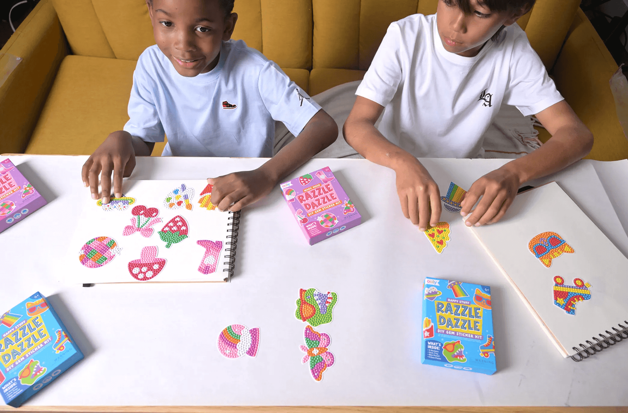 Two children sitting at a table with coloring books and crayons, engaged in an activity.