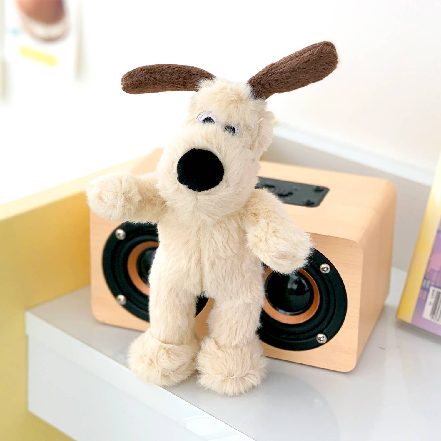Plush dog toy with brown ears on a wooden speaker