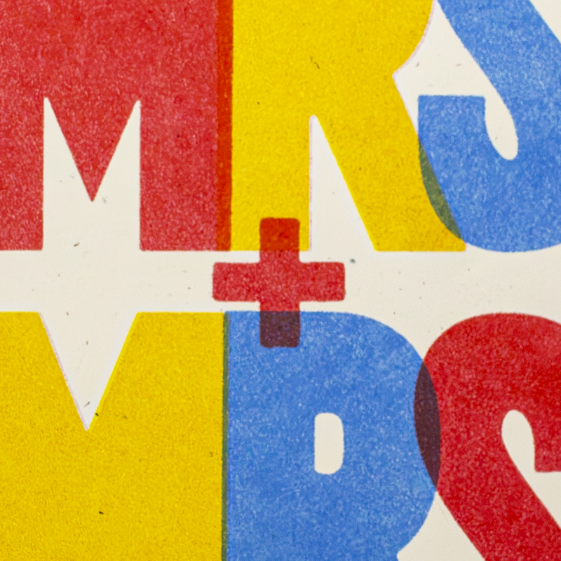 A close-up of bold retro-style lettering in red, yellow, and blue on a white background, with overlapping letters and a small red plus sign near the center.