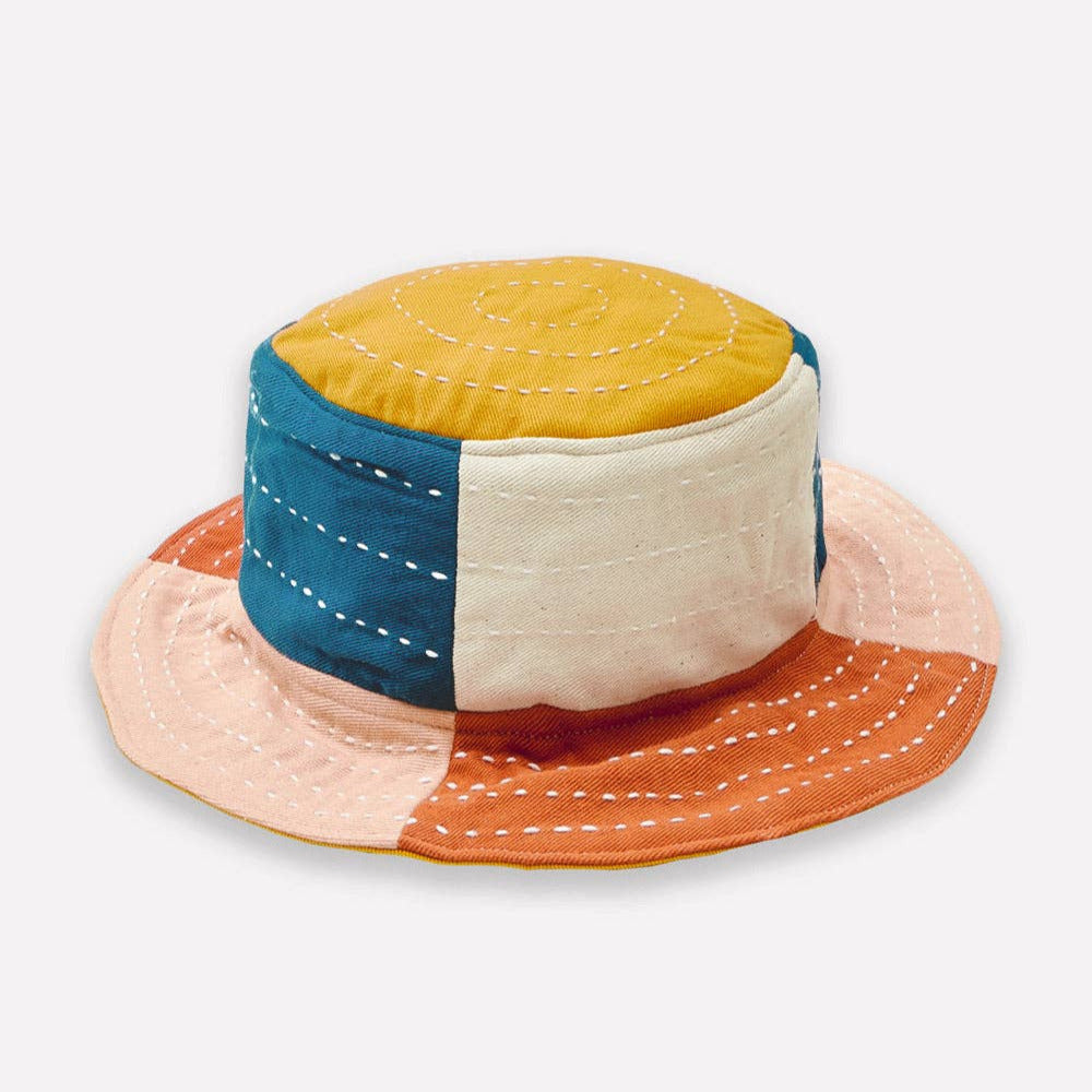 Color-blocked bucket hat with yellow, blue, beige, and orange sections on a white background.