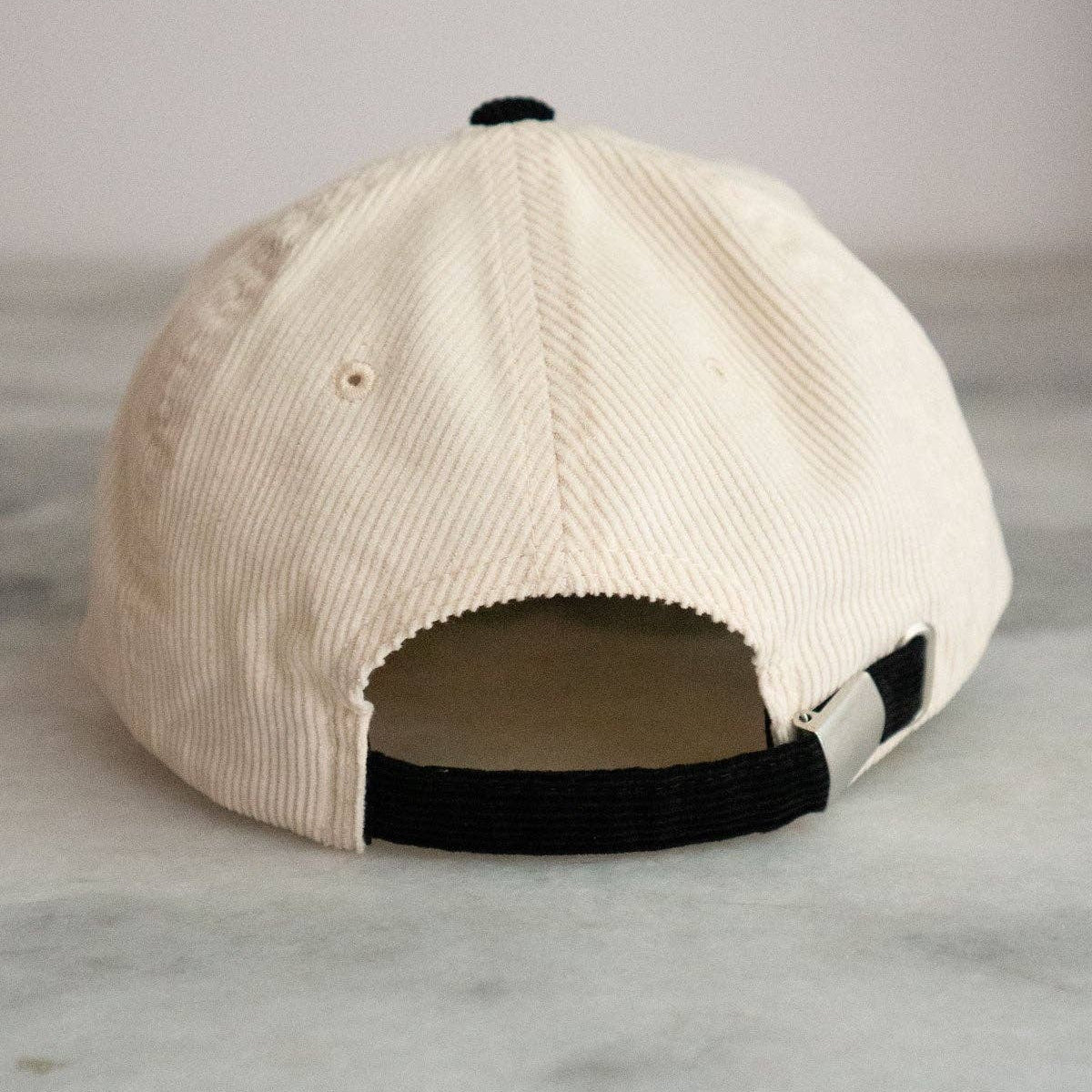 Beige cap with black accents on a marble surface