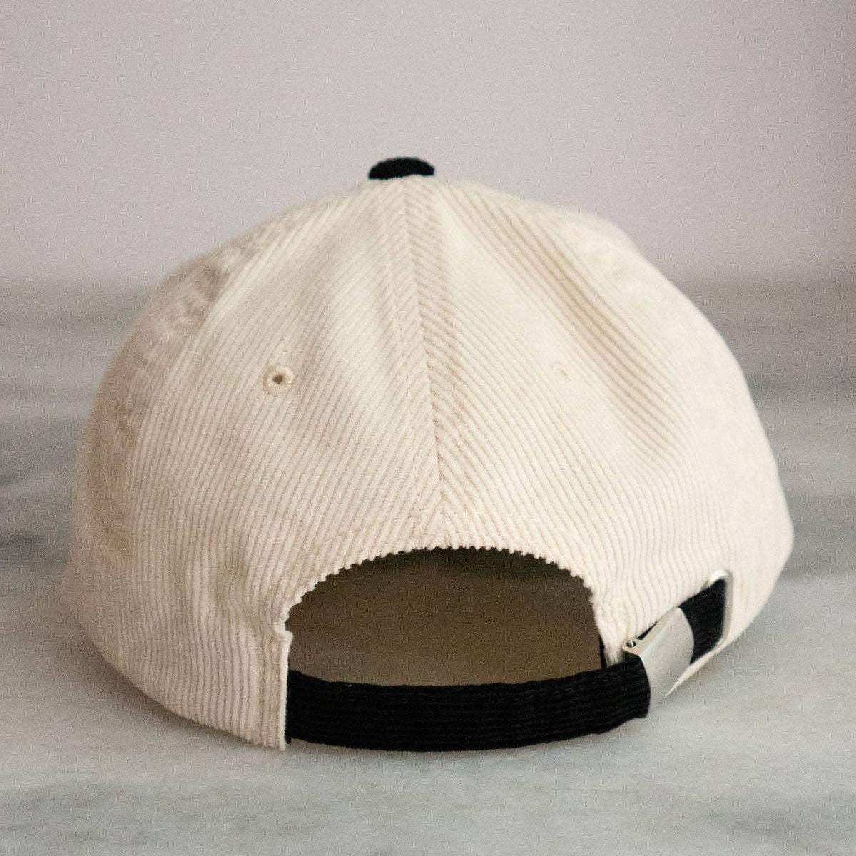 Beige cap with black accents on a marble surface