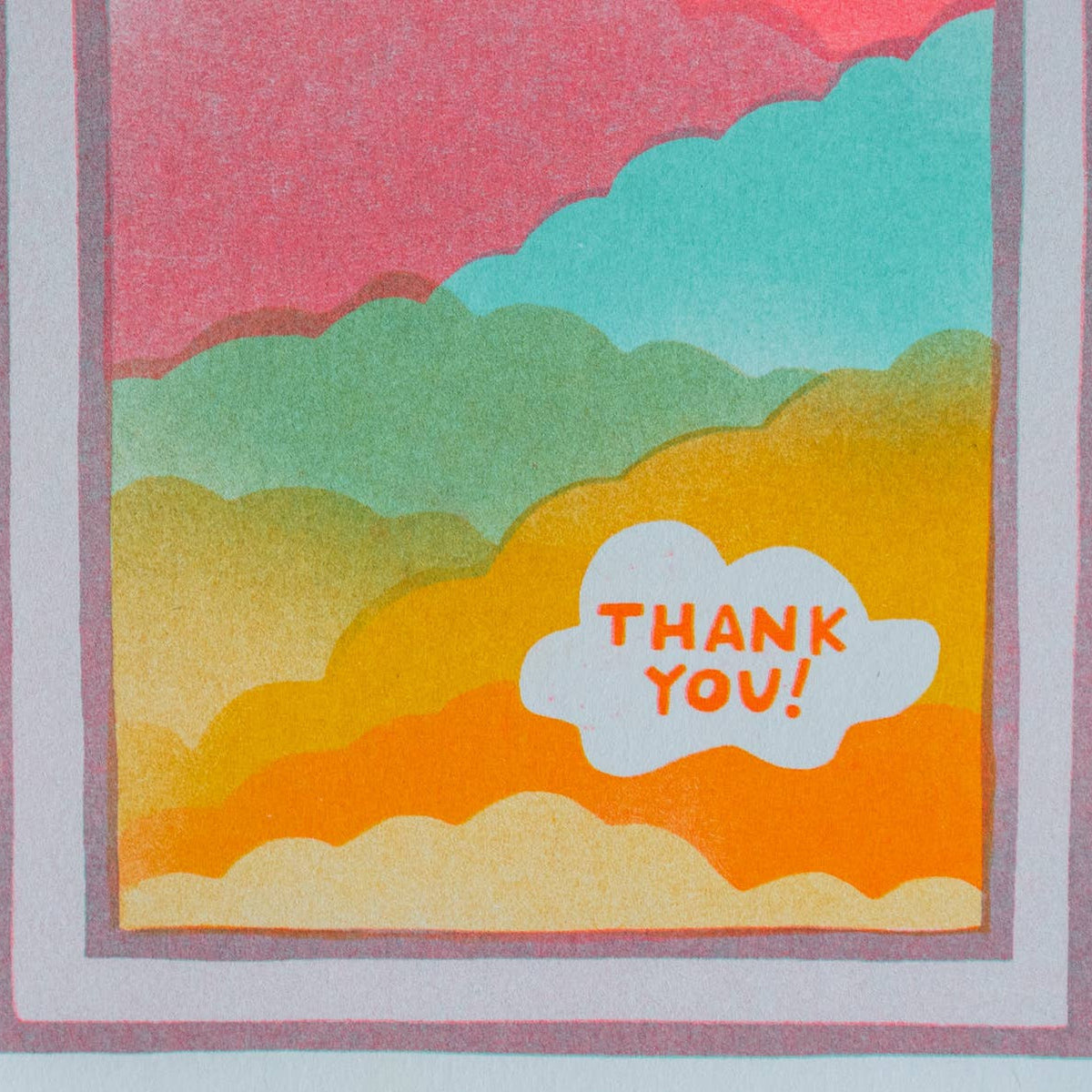 A close-up of a layered greeting card featuring a colorful sunset-style cloud design with the words 'THANK YOU!' in a white cloud shape, shown against a light gray background.