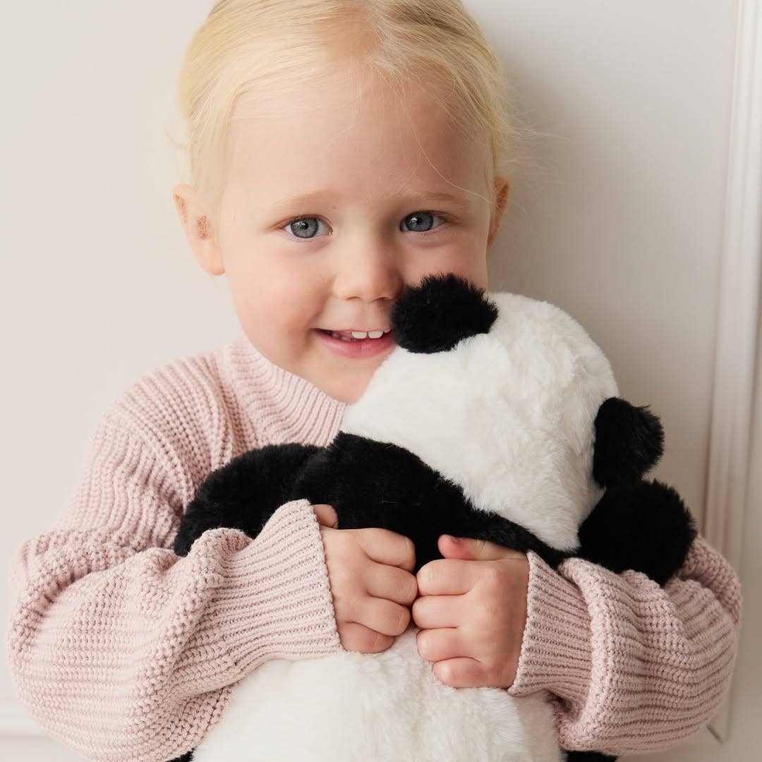 Child holding a panda plush toy against a plain background
