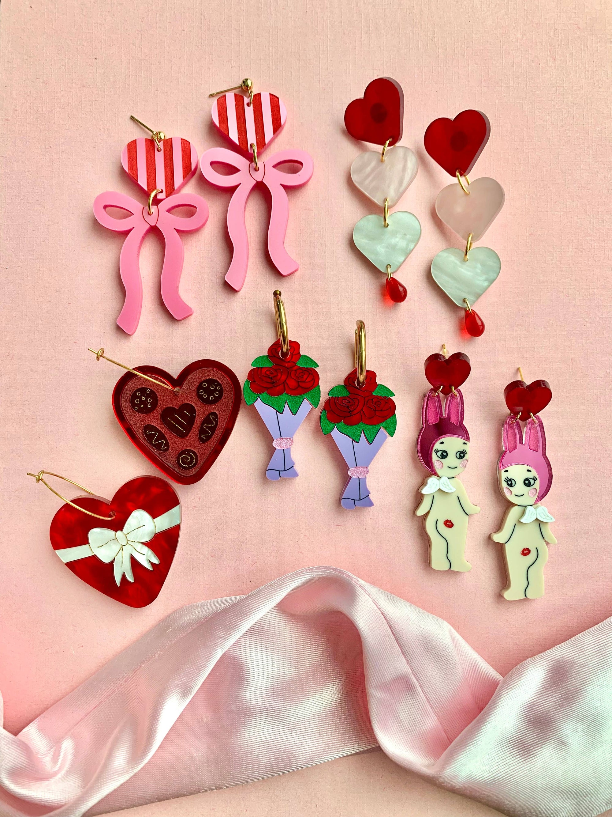 Colorful earrings on a pink satin fabric background