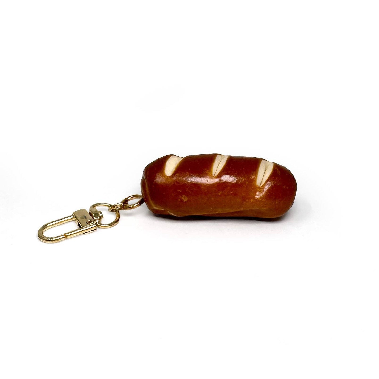 Bread-shaped keychain with a gold ring on a white background