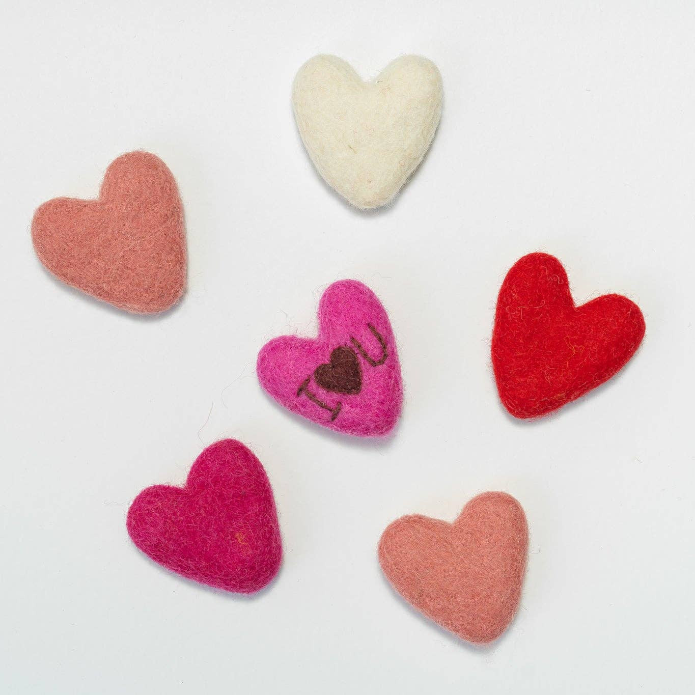Set of colorful heart-shaped felt decorations on a light gray background