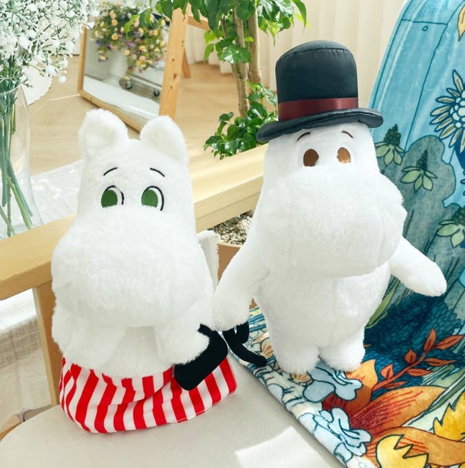 Two plush toys resembling characters from a children's show sitting on a couch.