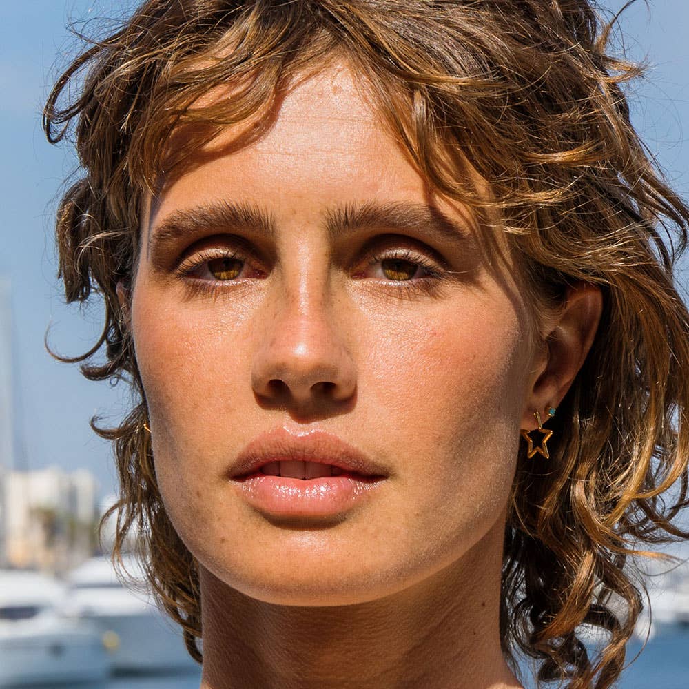 Close-up of a person with wavy hair against a blurred outdoor background