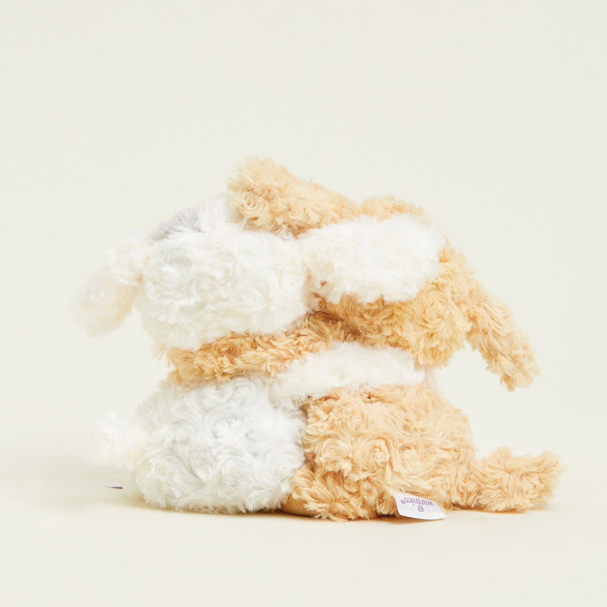 Plush toy resembling a dog with a white and beige color scheme on a light background