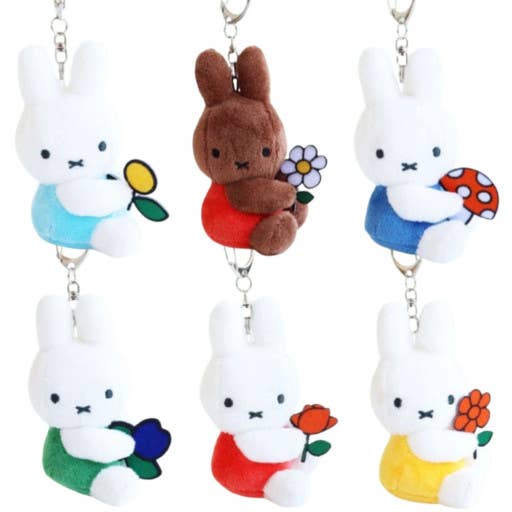 Set of five cartoon character keychains with colorful outfits and flowers on a white background