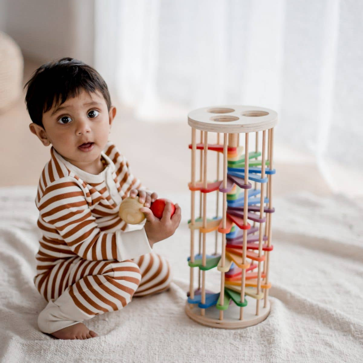 Child playing with a colorful wooden toy on a bed